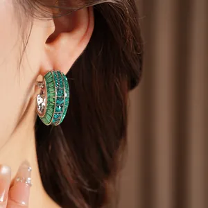 Close-up detail of luxury emerald green crystal inlaid silver needle hoop earrings on ear