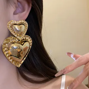 Detailed view of oversized double-layered gold heart earrings with ruffled edges