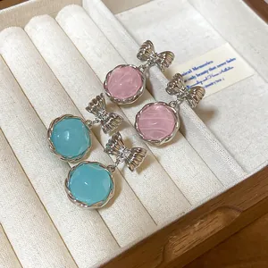 Close-up of sweet bow drop earrings with round pink and teal resin beads in a gift box