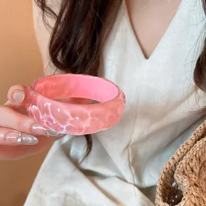 Macro view of a pink resin bangle featuring an irregular hammered texture with fine glitter