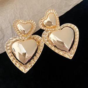 Close-up of vintage gold double heart drop earrings with elegant ribbed pleated edges