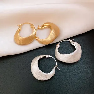 Detail shot of vintage 18K gold and silver plated hoop earrings with brushed texture