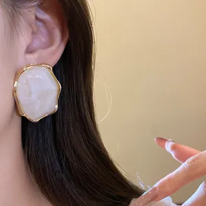 Primer plano de elegantes pendientes de resina con un borde dorado rugoso vintage