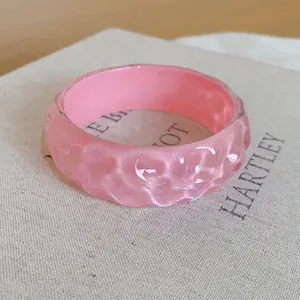 Close-up of pink resin bracelet with irregular textured surface and glossy finish