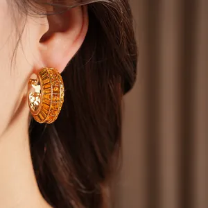 Detailed view of luxury gold-toned hoop earrings set with orange amber geometric crystals