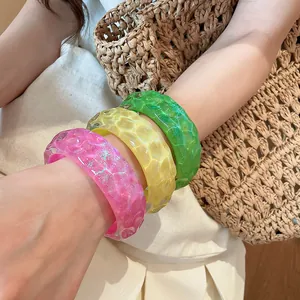 Close-up of three colorful resin bangles with irregular hammered texture on a wrist