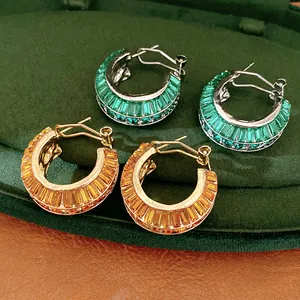 Detail showing luxury gold and silver hoop earrings with emerald and amber stones
