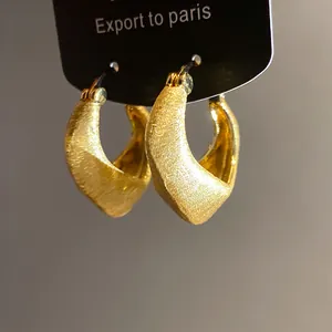 Close-up of retro 18K gold plated hoop earrings with elegant brushed metal texture.