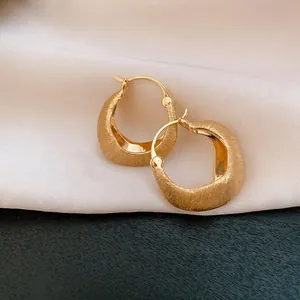 Macro view of 18K gold plated hoop earrings featuring a sophisticated brushed metal texture