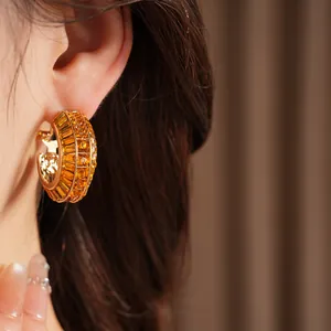 Detailed view of luxury gold hoop earrings encrusted with amber crystals on ear