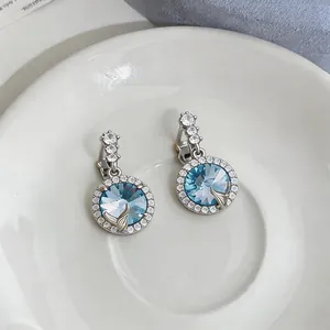 Dettaglio ravvicinato di eleganti orecchini in cristallo blu con coda di sirena.
