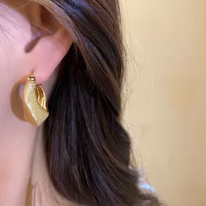 Close-up view of vintage 18K gold plated hoop earring with elegant brushed texture finish.