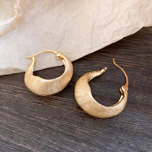 Close-up of 18K gold plated earrings with a brushed metal texture finish
