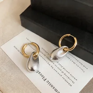 Detail shot of elegant two-tone hoop earrings with silver wrinkled teardrop pendants