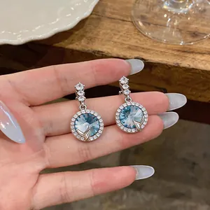 Dettaglio di orecchini di cristallo blu con finitura argento e dettaglio coda di balena