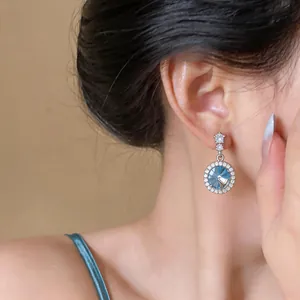 Primo piano di eleganti orecchini tondi con cristallo blu e bordo in pavé lucido