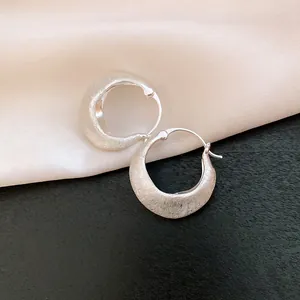 Macro detail of vintage brushed metal hoop earrings with elegant textured finish and design