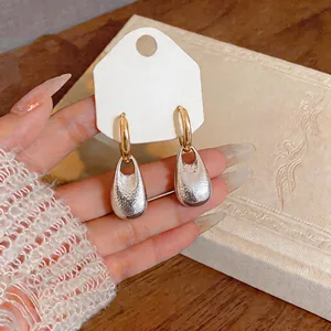 Detailed macro view of French style textured silver teardrop earrings with gold hoops