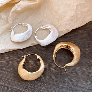 Close-up macro detail of 18K gold plated and silver brushed texture hoop earrings