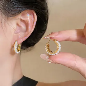 Close-up of French-style gold hoop earrings with delicate white pearl accents