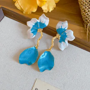 Close-up detail of French-style blue and white petal drop earrings displayed on a tray.