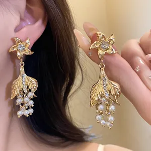 Exquisite Details von goldenen Fischtail-Ohrringen mit Strasssteinen und Perlen