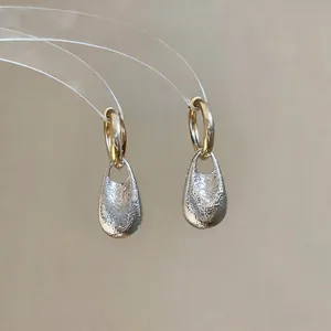 Detail view of French style teardrop hoop earrings with silver textured crinkle finish.