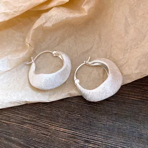 Close-up of elegant brushed silver round hoop earrings with a vintage crescent shape design