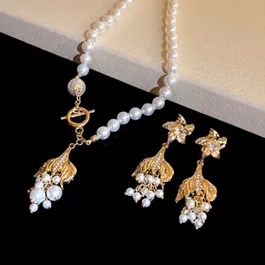 Nahaufnahme von Perlenkette und Ohrringen mit goldenen Fischschwanz-Anhängern