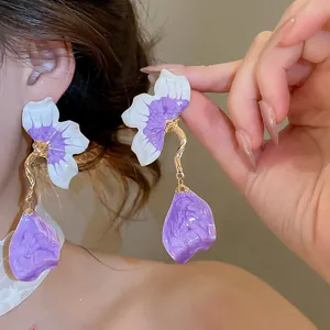 Macro detail of elegant purple flower petals and gold tassel drop earrings for women