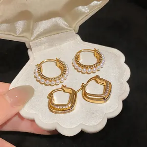 Macro detail of French style zircon rhombus and pearl hoop earrings in a shell box