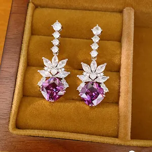 Close-up of elegant purple zirconia drop earrings in a wooden display box.