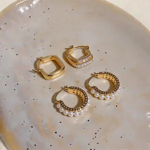 Elegant French style gold square hoops and pearl hoop earrings set on ceramic plate