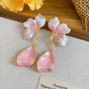 Close-up detail of elegant pink enamel flower petal drop earrings with golden stem