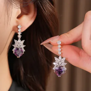 Macro detail of elegant purple rhombus drop earrings with sparkling marquise zirconia stones