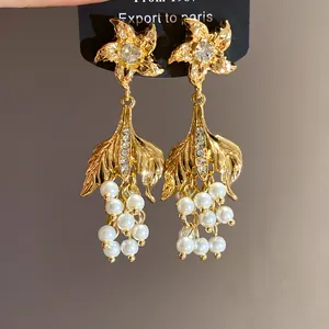 Detailansicht von goldenen Vintage-Ohrringen mit Strasssteinen und weißen Perlenanhängern