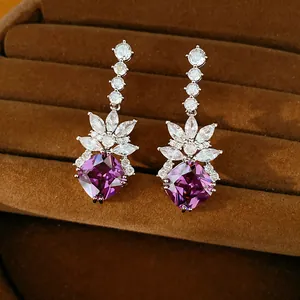 Close-up of elegant long drop earrings with purple square zircons in a brown velvet case