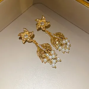 Detail von Vintage-Ohrringen in Goldoptik mit Strasssteinen und Perlen in einer Box.