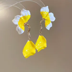 Macro detail of French style yellow and white enamel petal earrings with gold tassel drop.