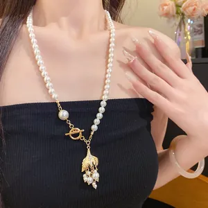 Nahaufnahme einer Vintage-Perlenkette mit einem goldenen Fischschwanz-Anhänger-Detail