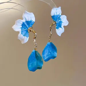 Macro detail of French style blue and white enamel petal tassel earrings with gold finish