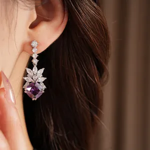 Close-up of elegant purple geometric zircon dangling earrings on an Asian model ear for fashion