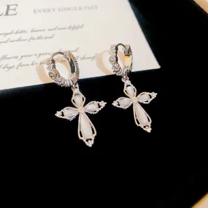 Close-up detail of silver cross hoop earrings with sparkling zircon and white inlay.