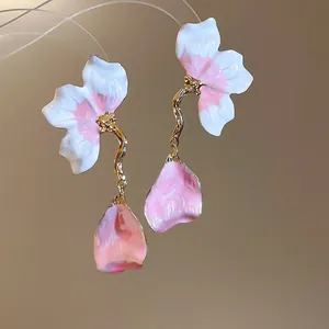 Close-up of elegant pink and white enamel flower petal tassel earrings with gold finish