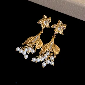 Detailaufnahme der Vintage-Goldohrringe mit Fischschwanzanhängern und Perlenclustern