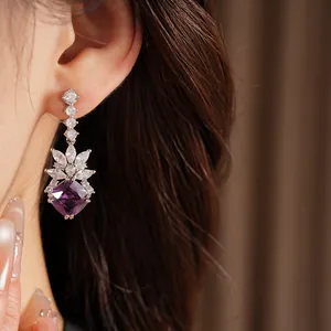 Detailed close-up of geometric purple crystal drop earrings with cubic zirconia