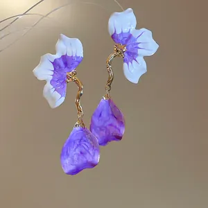 Macro detail of French style enamel flower petal drop earrings in purple and gold