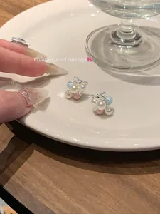 Detailed view of colorful pearl bow earrings on a white ceramic plate lifestyle.