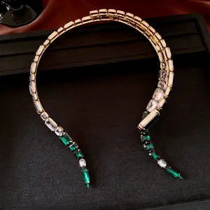 Primo piano della collana vintage geometrica dorata con cristalli verde smeraldo e chiari
