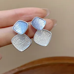 Nahaufnahme von texturierten Rauten-Ohrsteckern mit hellblauem Emaille und Silber-Finish